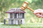 Property auction, Woman hand holding gavel wooden and locked house with padlock and chain on natural green background, lawyer of home real estate and ownership property concept.bankruptcy